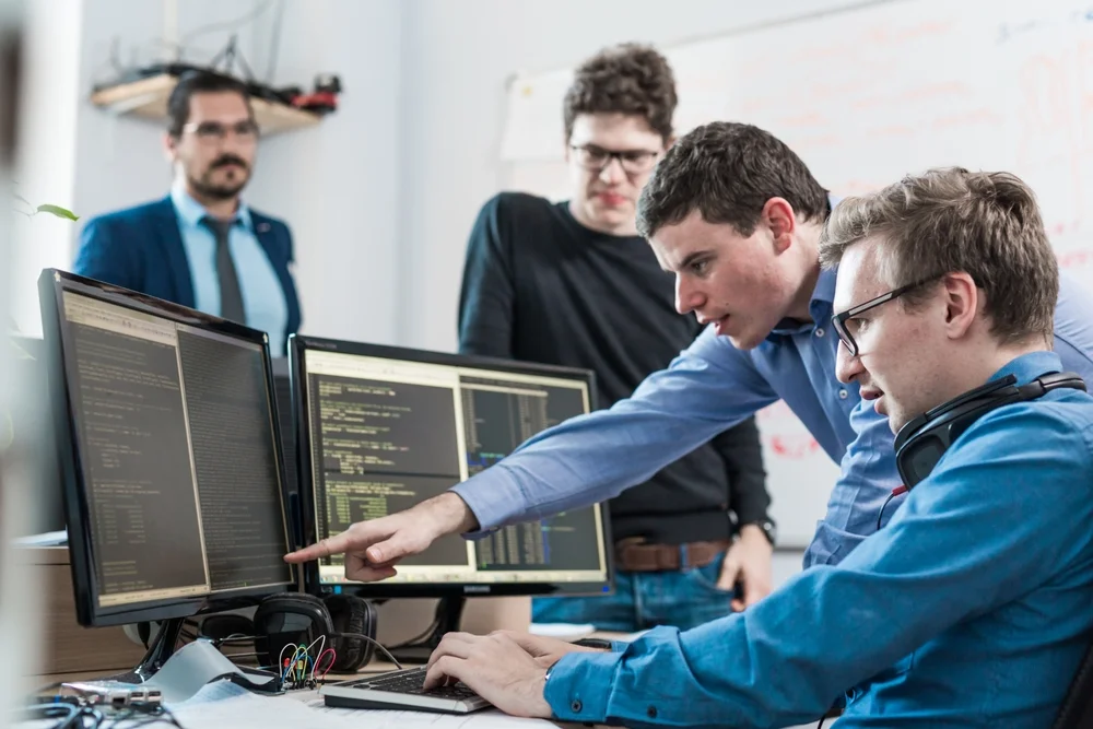 Young developers brainstorming UI solutions in a startup office, representing customization in Flutter vs React Native apps.