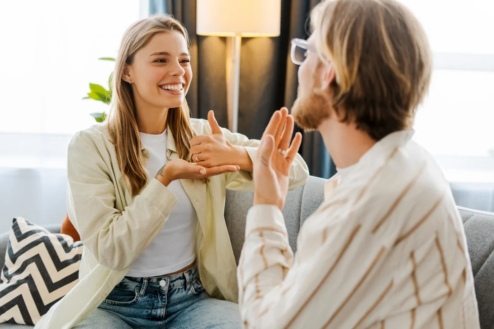 Young couple using sign language at home, highlighting inclusive communication and accessibility design.